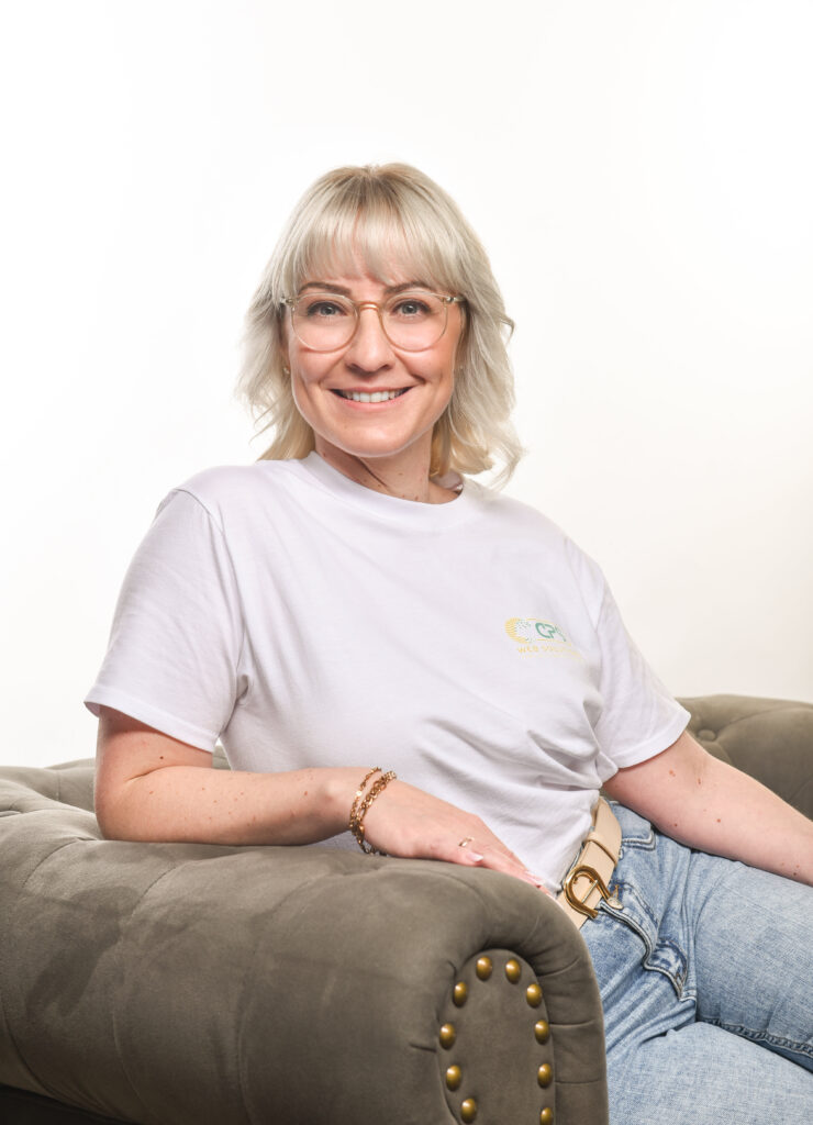 Carolin Störmer - Spezialist für verkaufspsychologische Websites lächelt in die Kamera während sie auf einem Sofa sitzt.