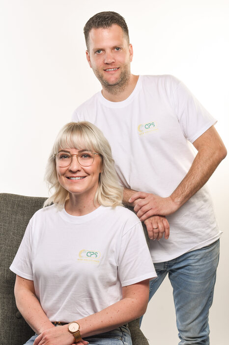 Carolin und Pascal Störmer von CPS Web Solutions. Carolin sitzt auf einem Sessel, während Pascal sich hinter ihm anlehnt.
